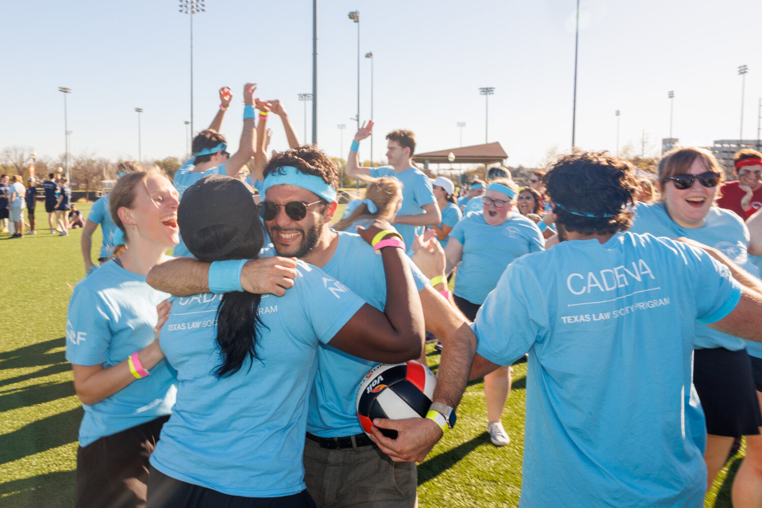 Students wearing light blue T-shirts on recreational field cheering