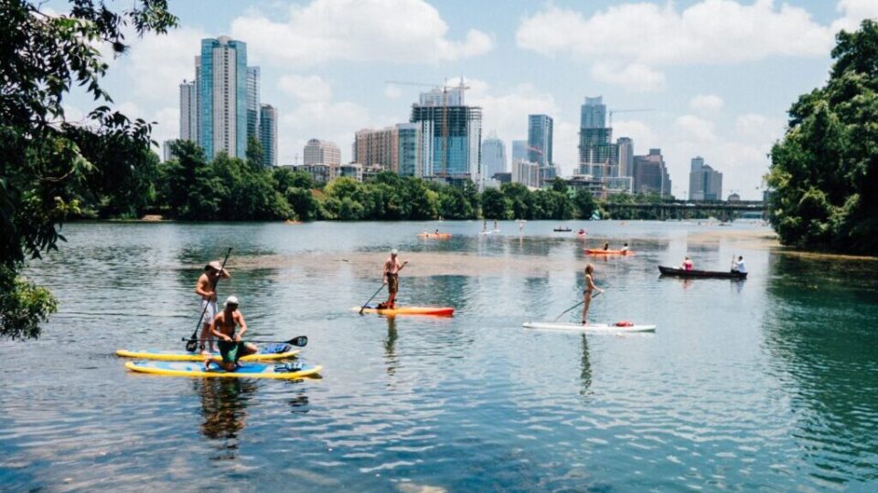 paddle boards on Lady Bird Lake with downtown in the background