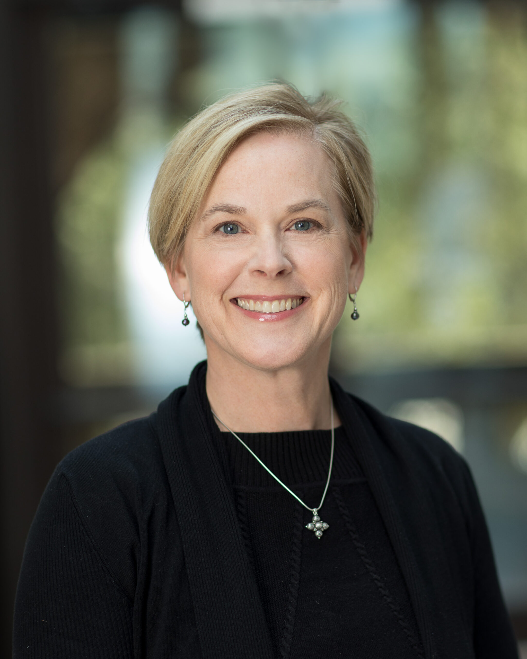 Portrait of Liz Hilton wearing a necklace over a black blouse.