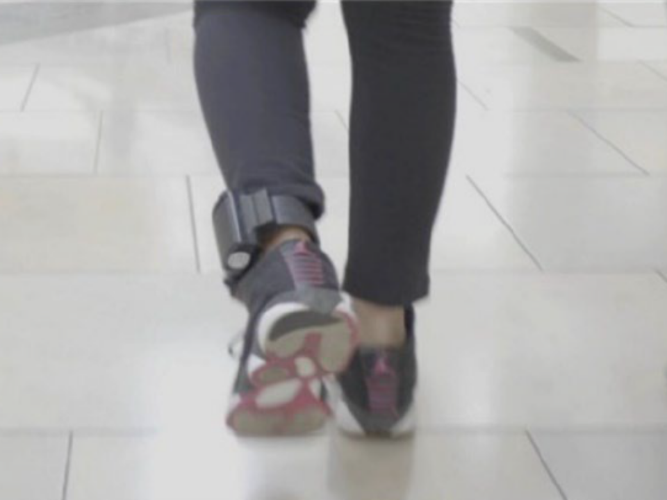 person walks with ankle monitor visible