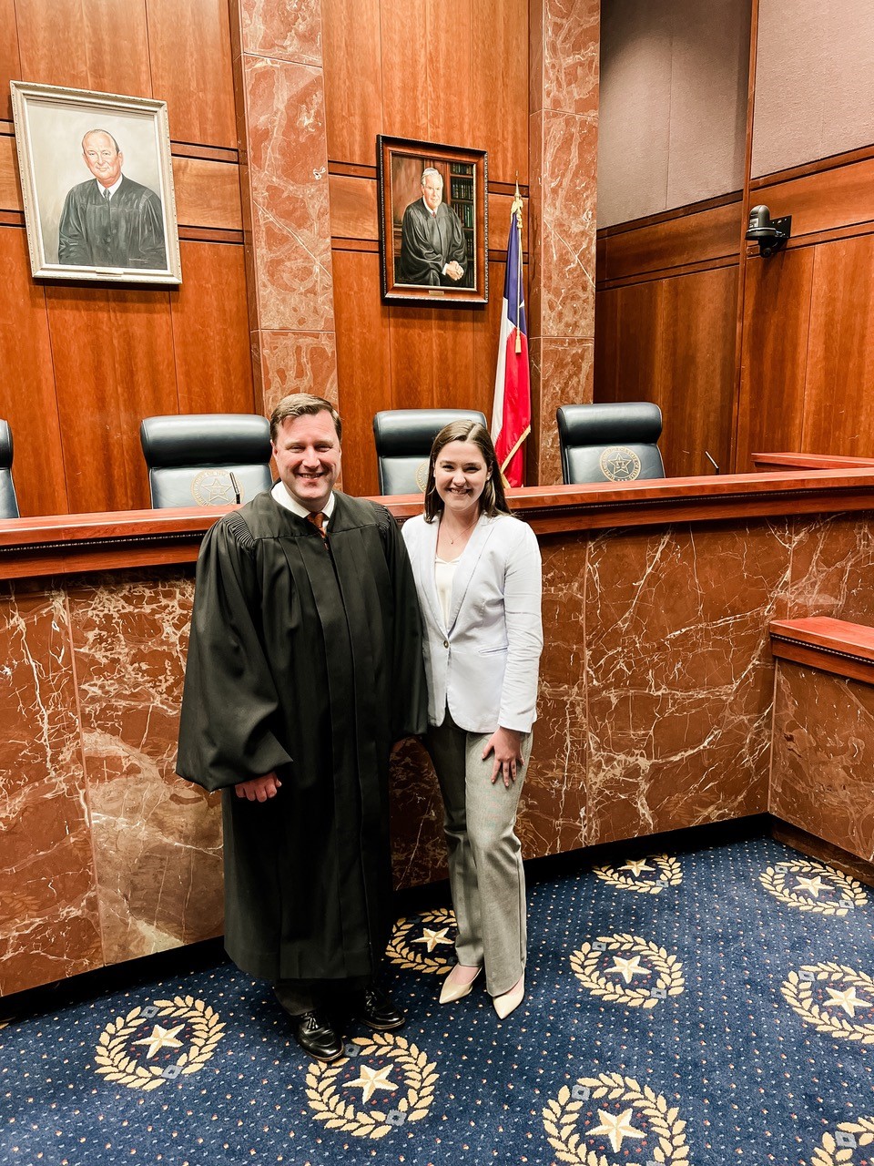 Judge and student pose in a courtroom