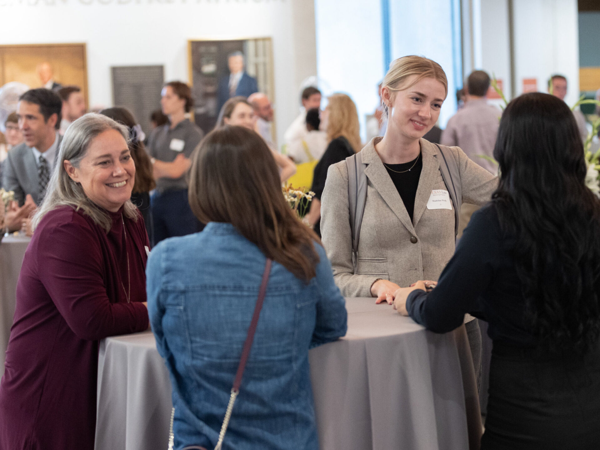 Mentors and mentees stand at tables talking to one another