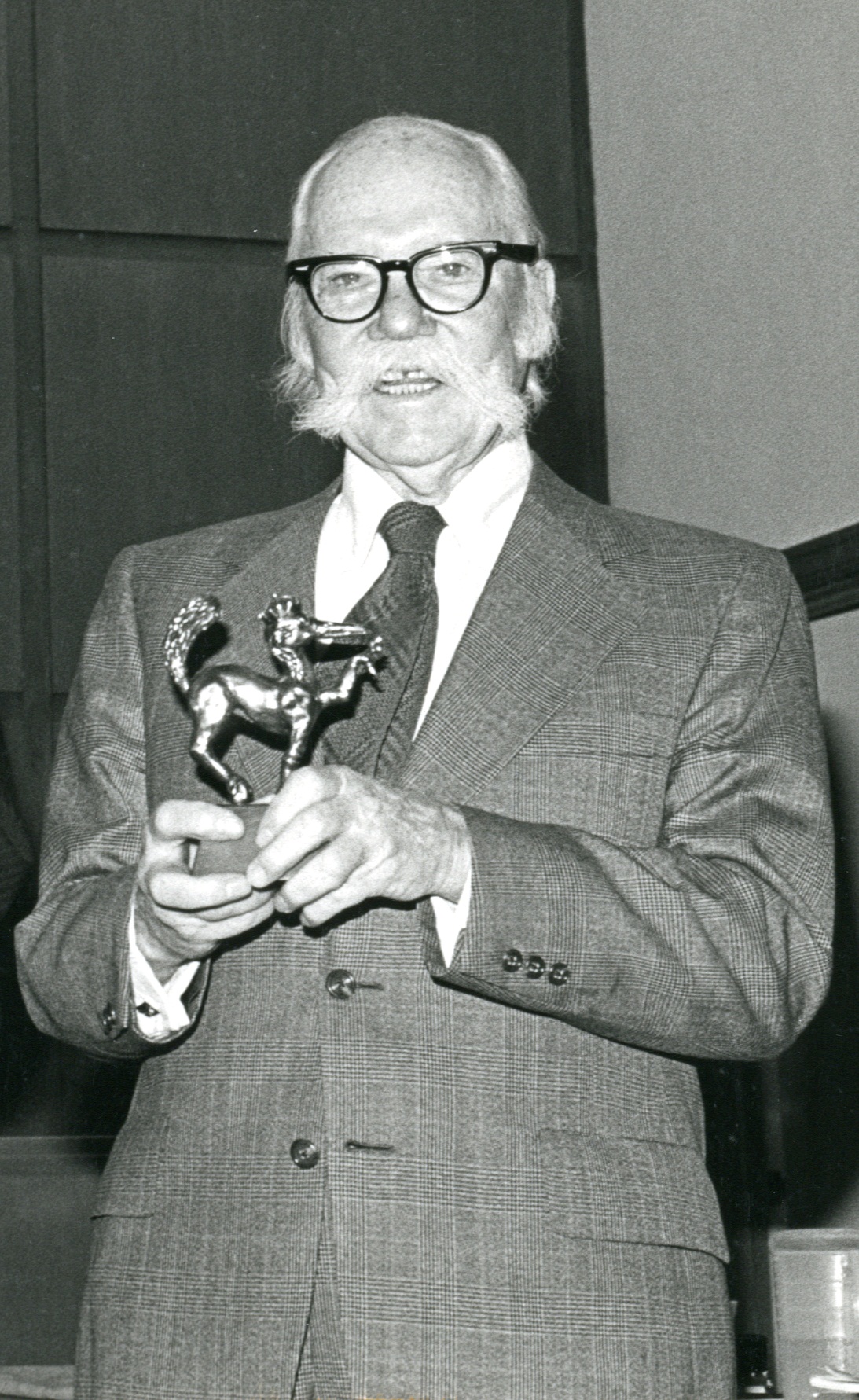Photo of Gus Hodges, '32 holding an award