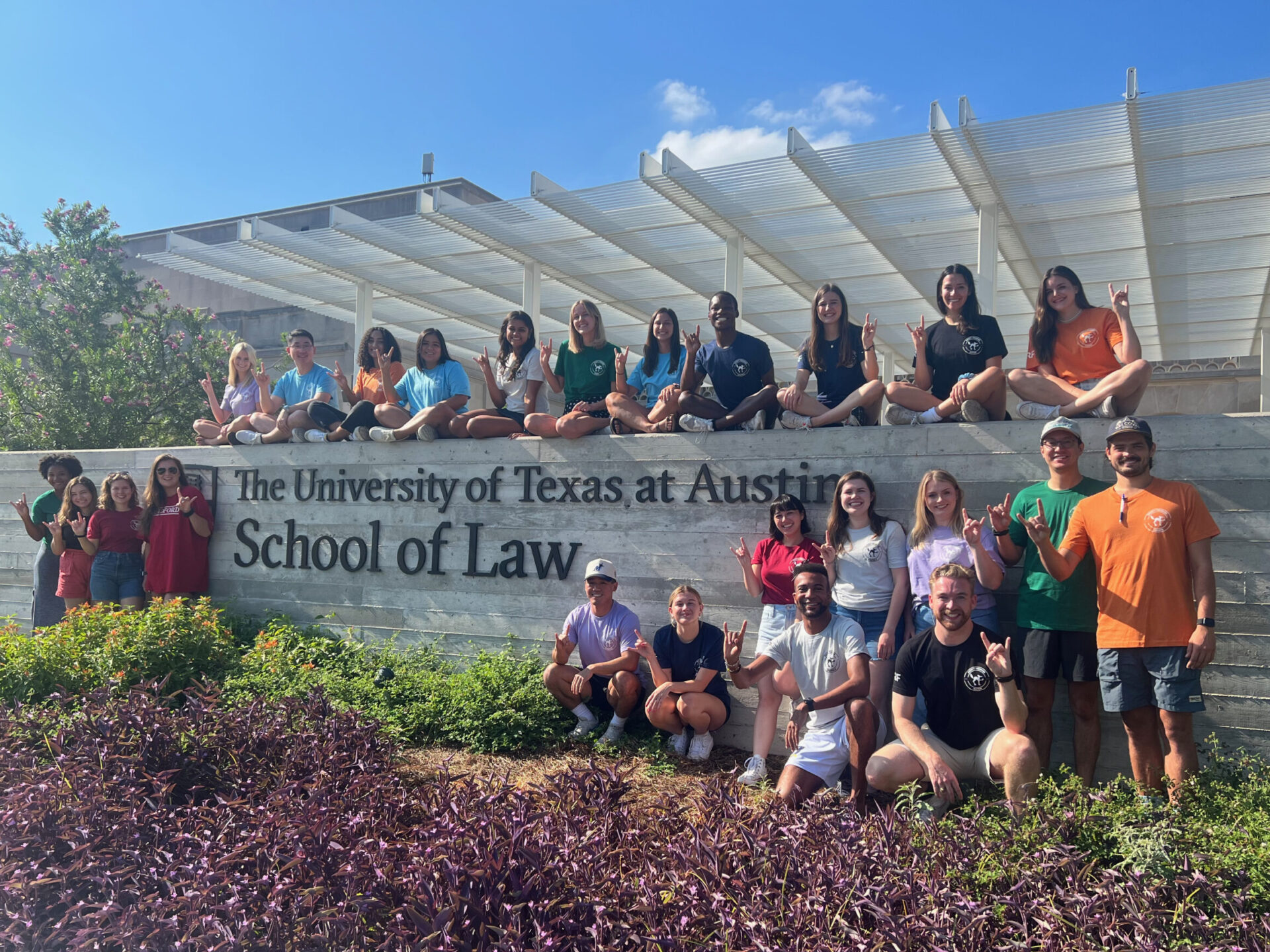 Law students sitting on wall with School of Law sign