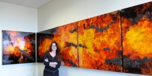Artist Mery Godigna Collet poses with panels from her piece, Pure Energy. Photo by Steph Swope.
