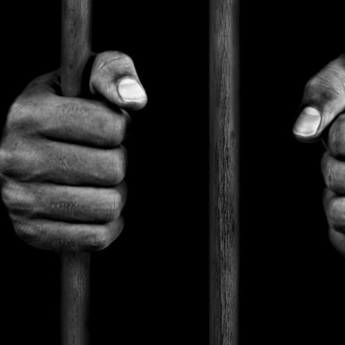 hands of an African-American holding onto jail bars