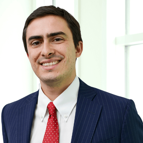 Picture of smiling man in dark suit with red tie.