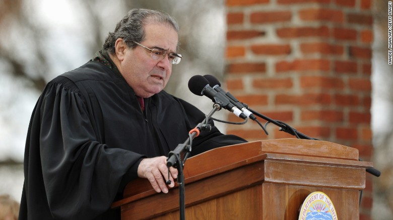 Judge standing behind a podium, speaking into a microphone