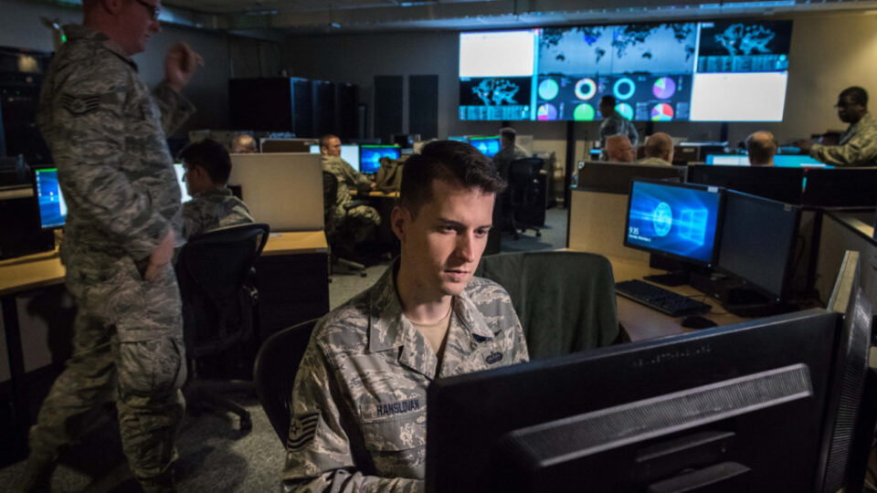 Individuals in front of their computers, dressed in military outfits.
