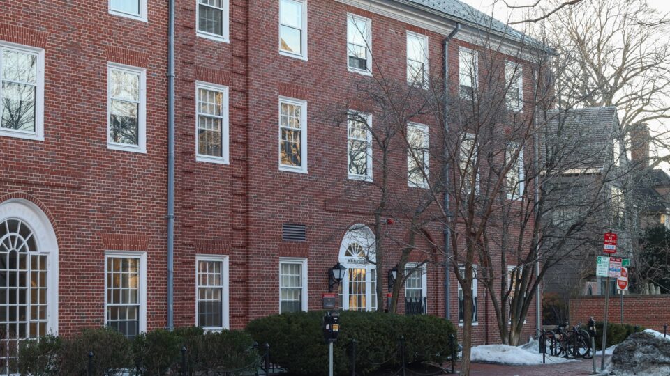 An image of a red brick building with several windows, on the Harvard campus.