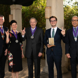 All the 2019 Alumni Award Winners, standing with their hands up in the