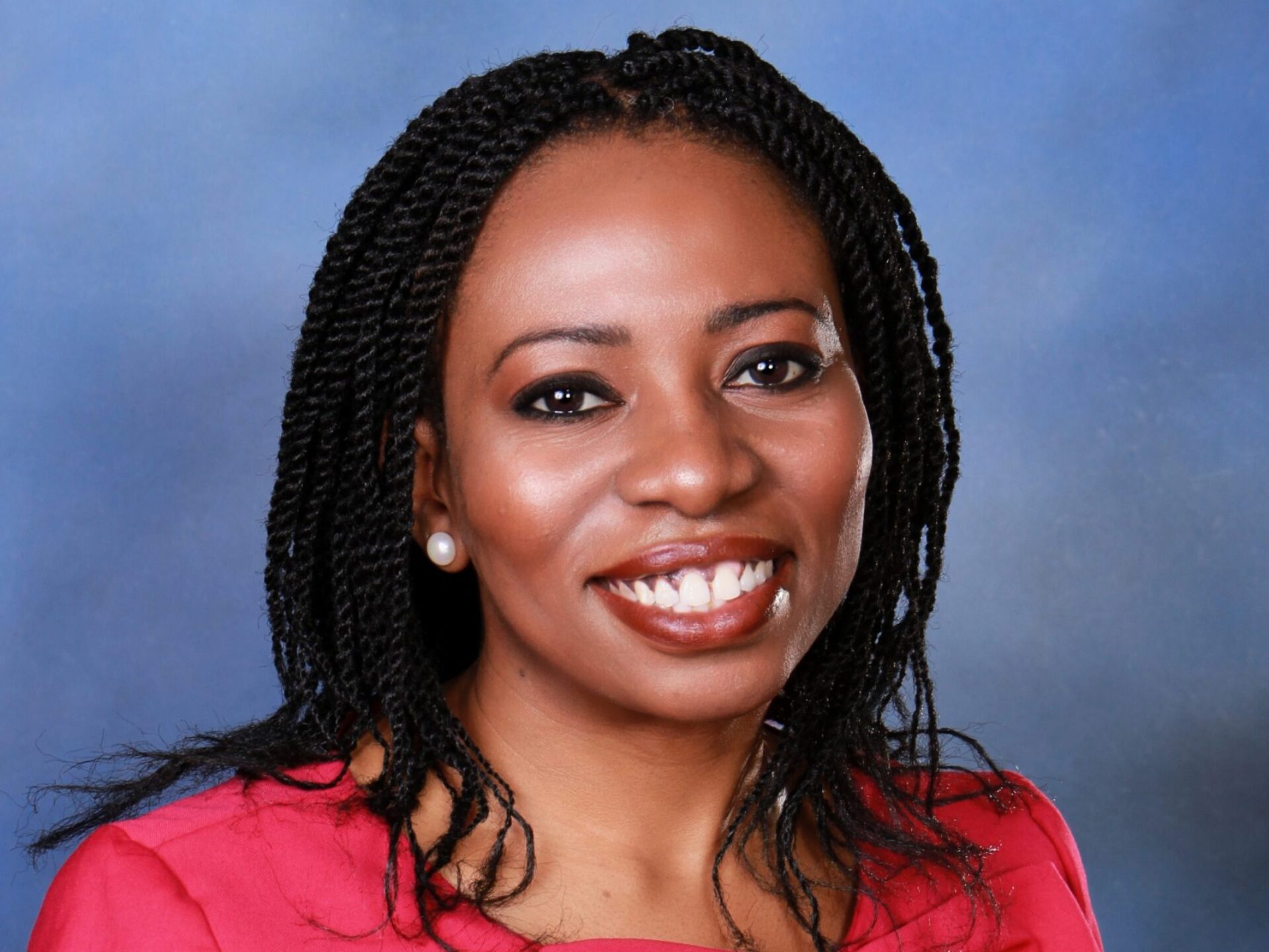Portrait of Cynthia Akatugba, wearing a pink shirt with a bow on it.