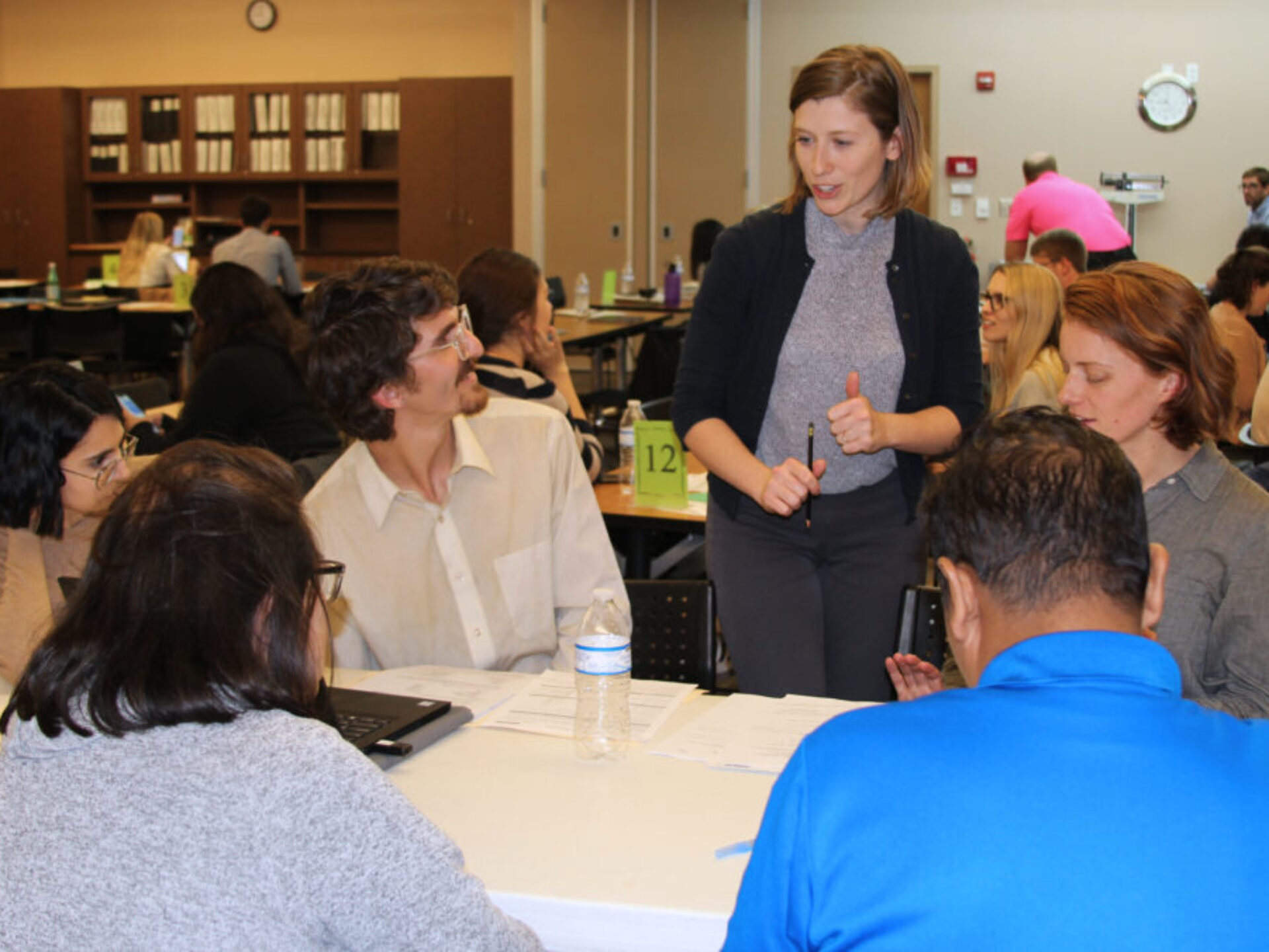 Eva Sikes standing and speaking to five students seated at a table during Pro Bono in January 2020.