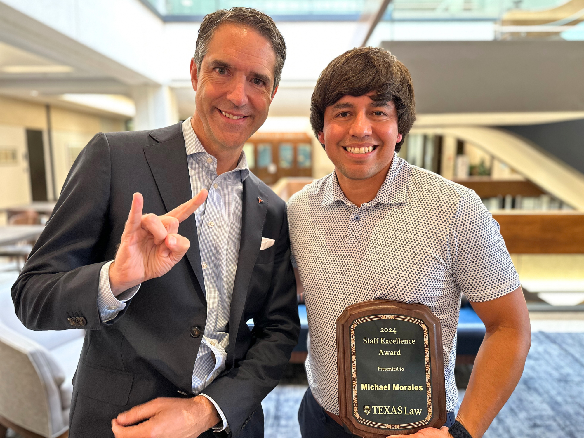 Michael Morales holds his 2024 Employee of the Year award and poses with Dean Bobby Chesney