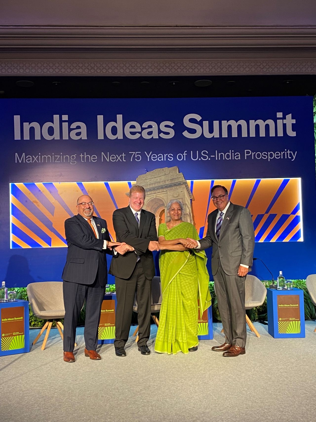 Four people shaking hands on a stage under a banner that reads, "India Ideas Summit"