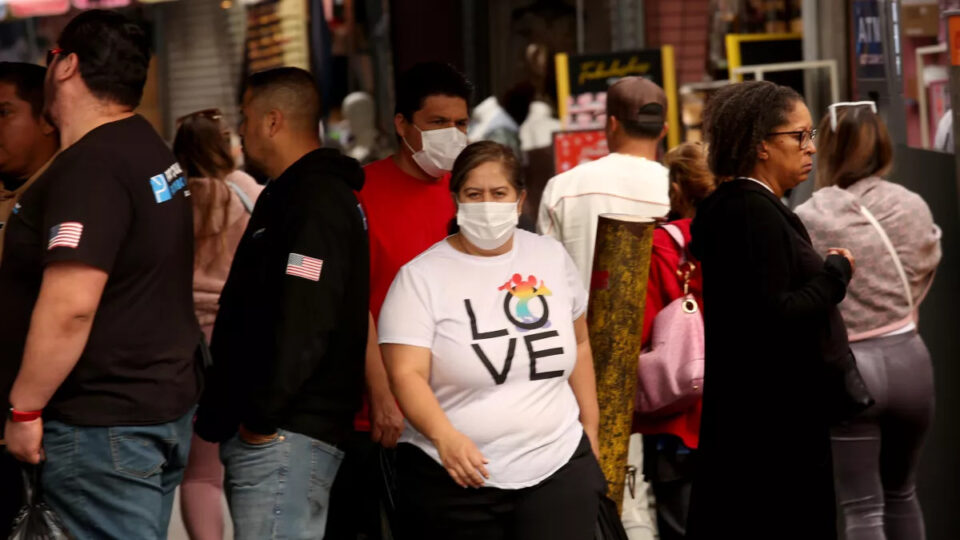 A masked shopper walks among a crowd at Santee Alley in LA.