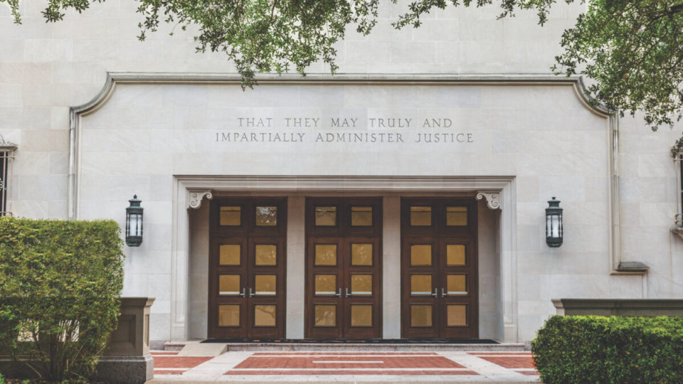 The exterior doors of Townes Hall at the University of Texas School of Law, with an inscription chiseled above: "That they may truly and impartially administer justice."