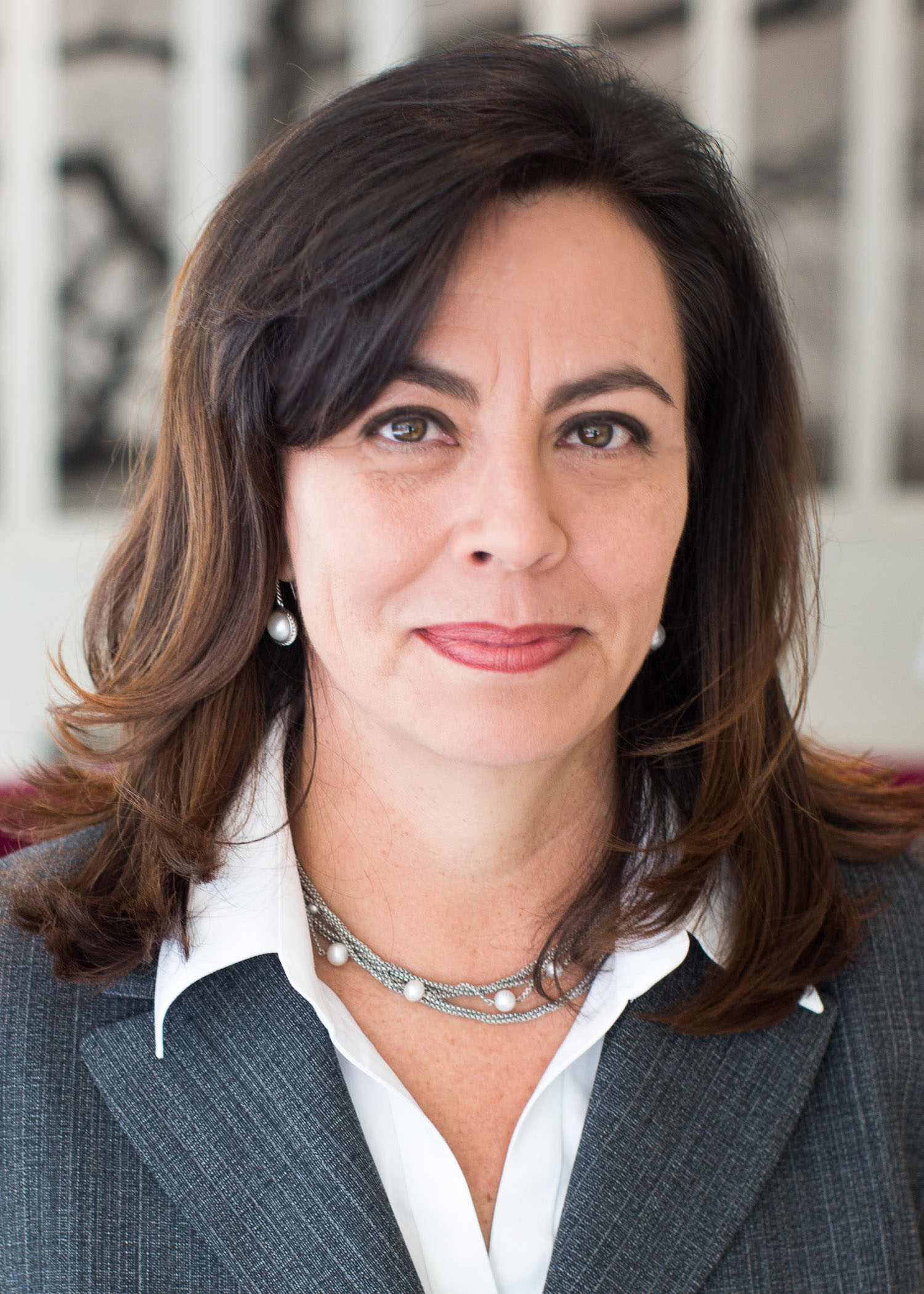 Portrait of Hilda Galvan, wearing a grey suit jacket and a necklace with pearls.