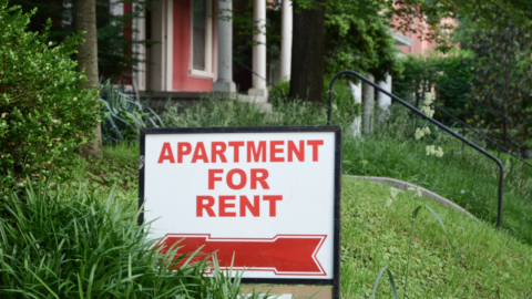 Apartment for rent sign displayed on residential street.