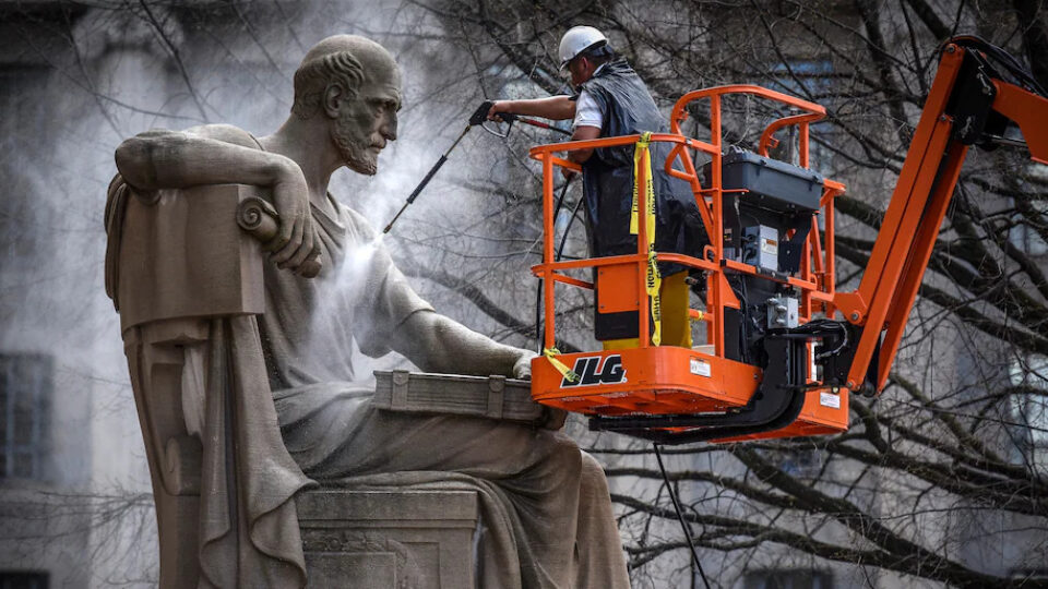 A worker cleans the 1935 statue of Socrates by Robert Aitken at the National Archives in 2017. (Bill O'Leary)