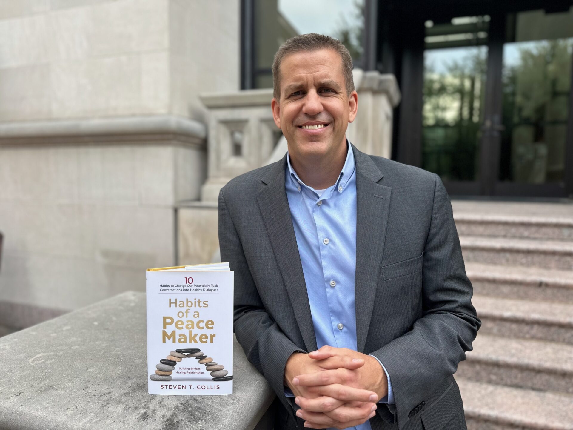 Steve Collis poses with his new book, 10 Habits of a Peacemaker