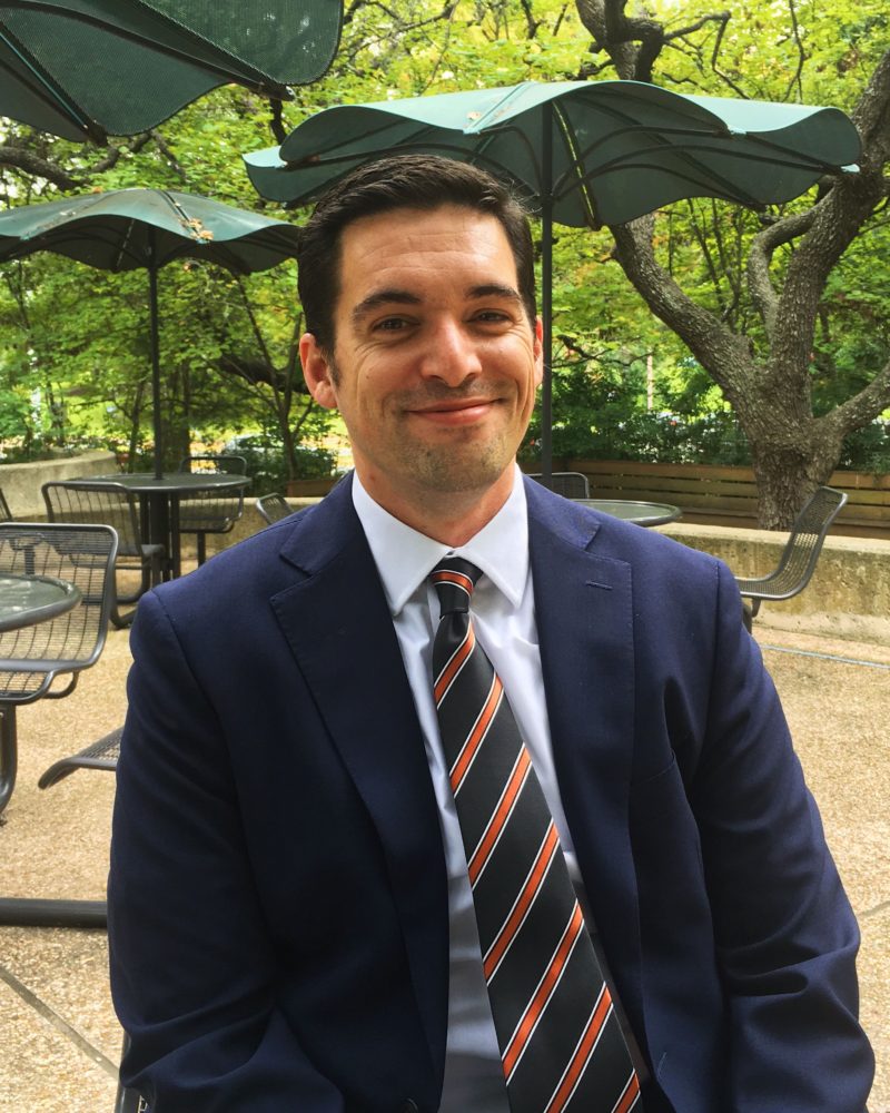 Dustin Farahnak, pictured in front of picnic benches and trees at The School of Law