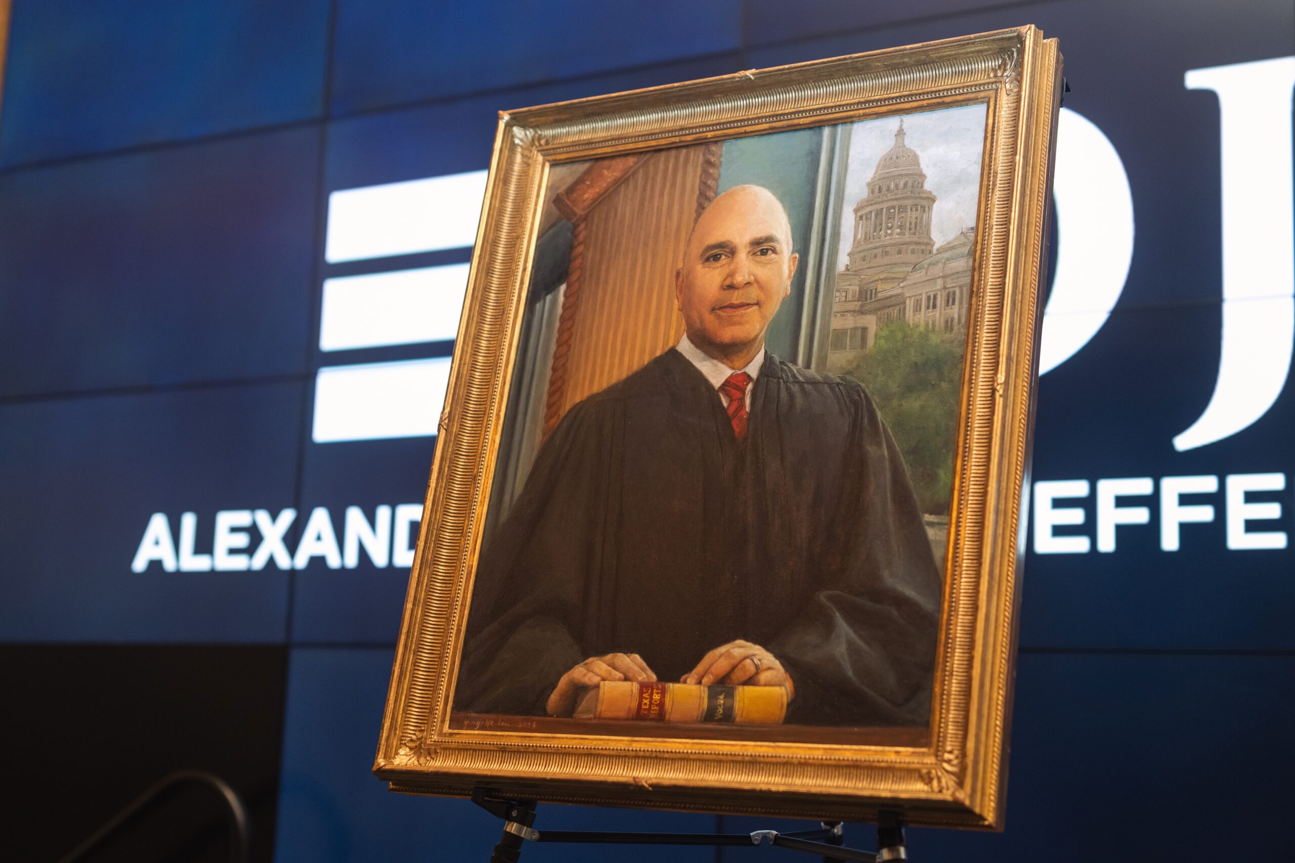 An oil portrait of The Honorable Wallace Jefferson stands on an easel.