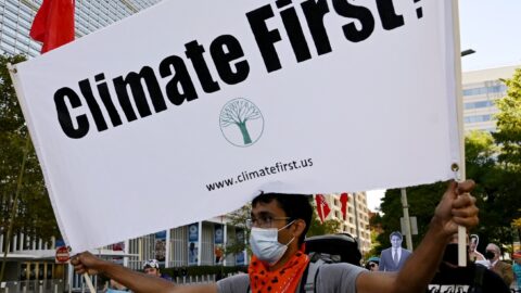 A protestor holds up a sign that reads "Climate First."