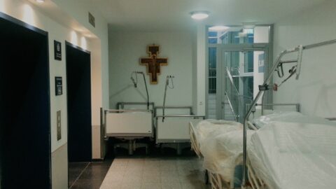 A photograph of a hospital room with a cross on the wall.