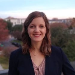 Portrait of Caitlin Machell Pevey, pictured in front of fall-colored trees