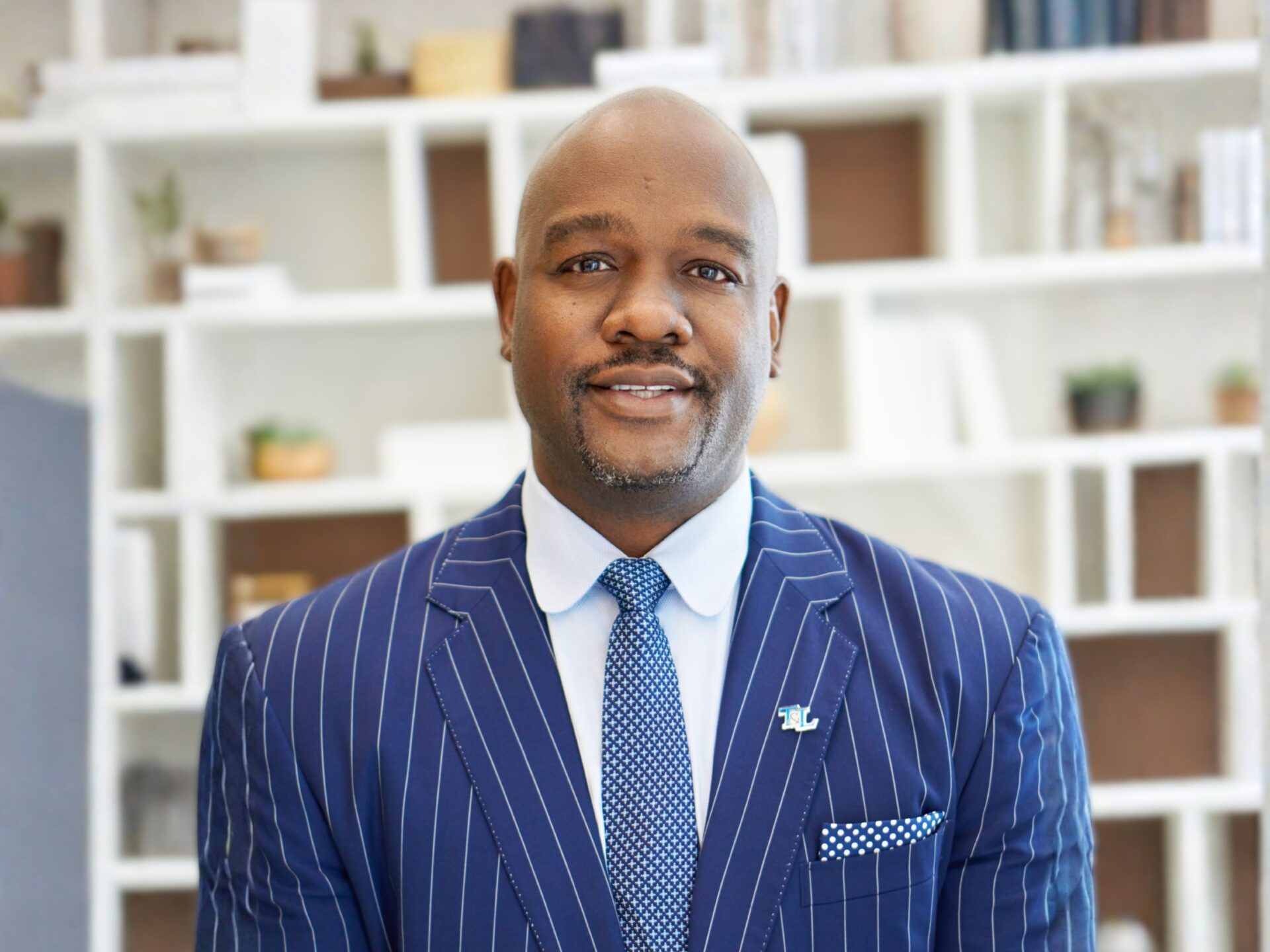 portrait of Marlen Whitley wearing a suite, in front of bookcase