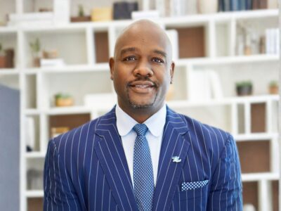 portrait of Marlen Whitley wearing a suite, in front of bookcase