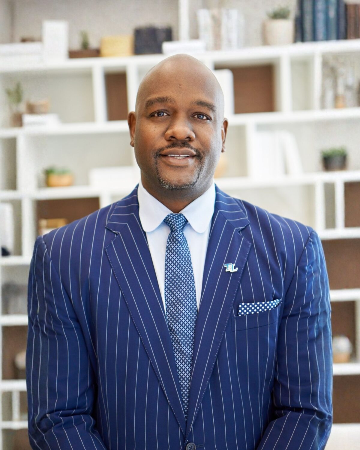 portrait of Marlen Whitley wearing a suite, in front of bookcase
