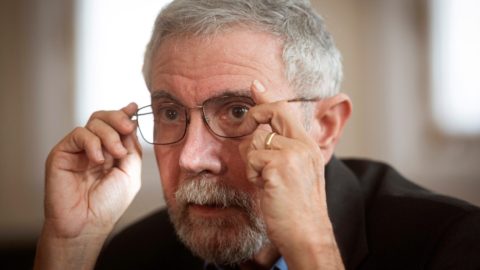 Portrait of Paul Krugman putting on his glasses.