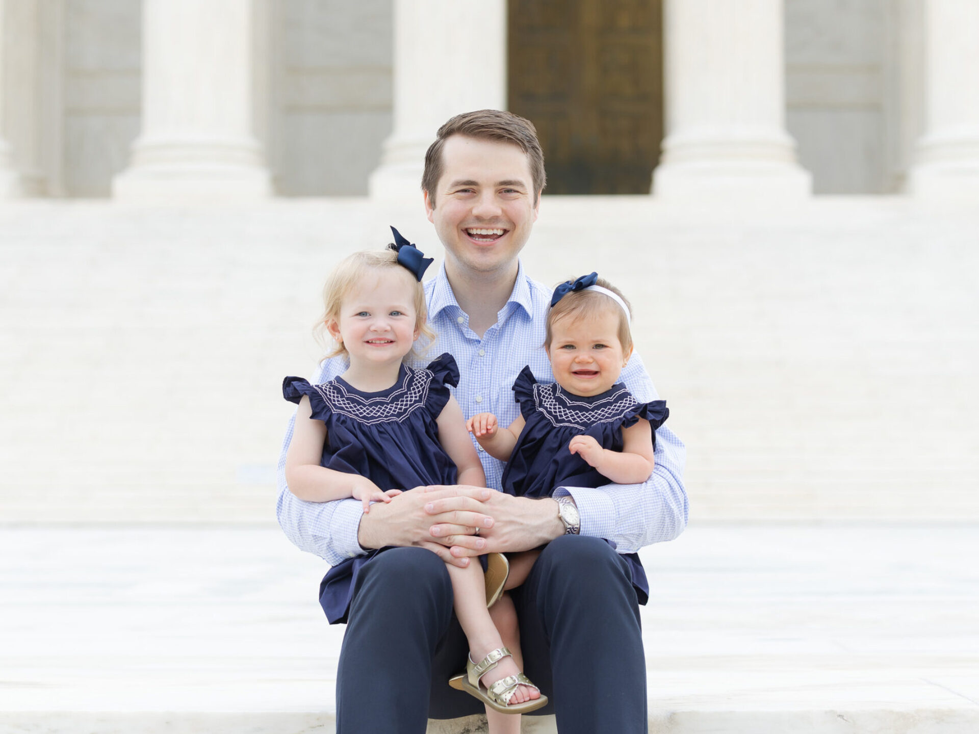 Photo of Reid Coleman and young daughters outside on the steps of the Supreme Court.