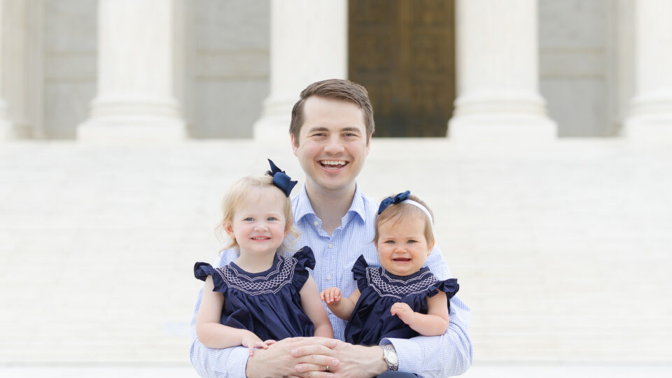 Photo of Reid Coleman and young daughters outside on the steps of the Supreme Court.