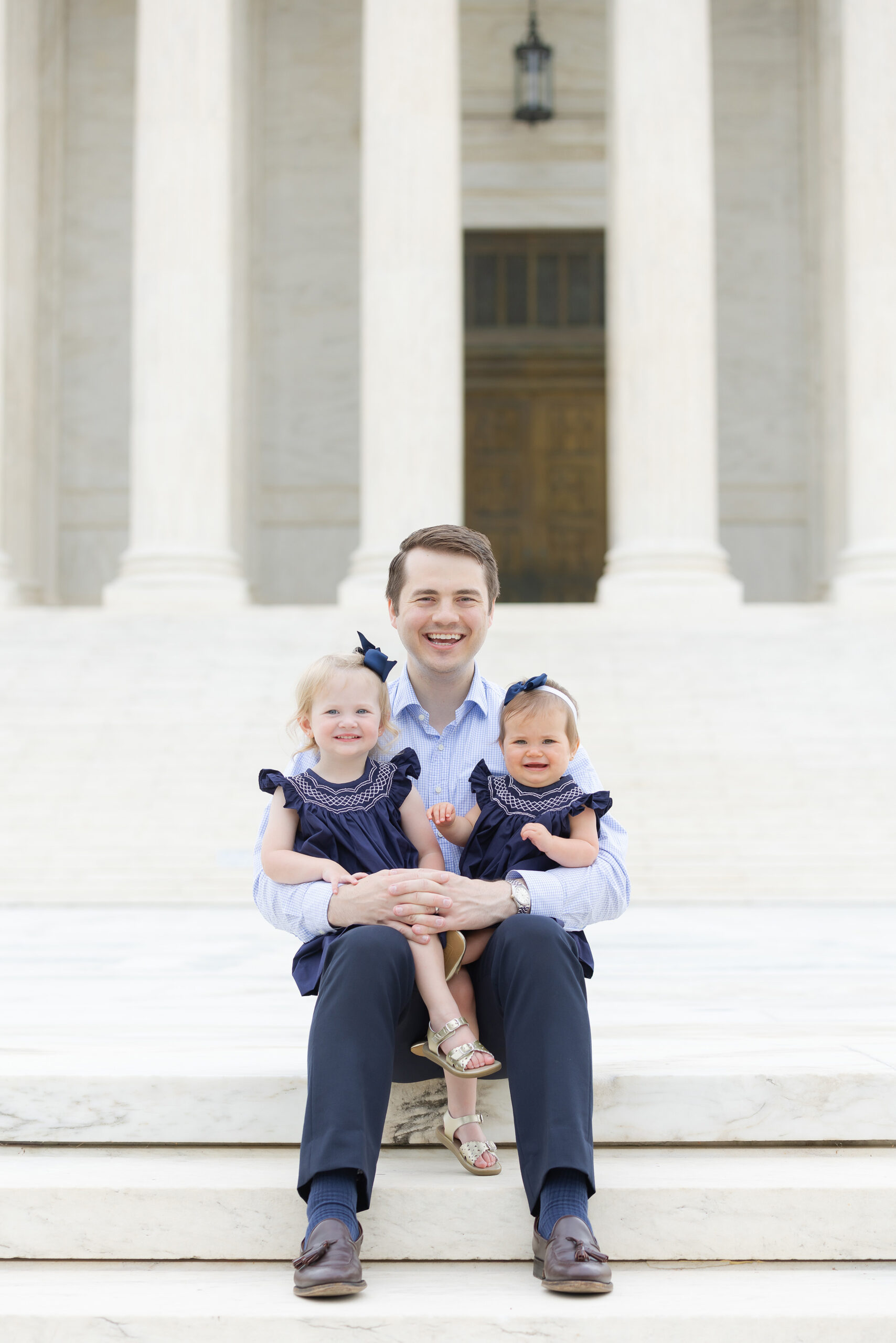 Photo of Reid Coleman and young daughters outside on the steps of the Supreme Court.