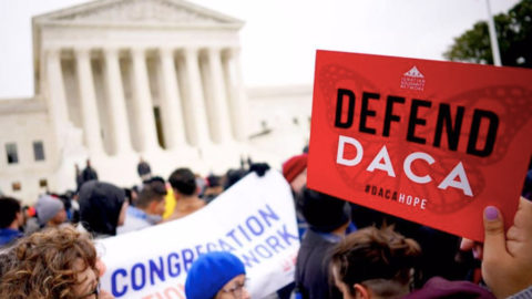 Protestors hold signs in front of the U.S. Supreme Court, with a "Defend D.A.C.A." sign held in the foreground