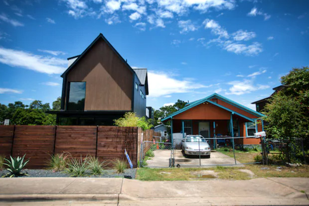 A modern, new-construction house next to a smaller one-story house