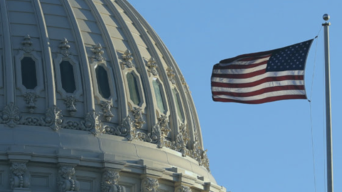 The United States of America flag flying next to the United States Capitol building.