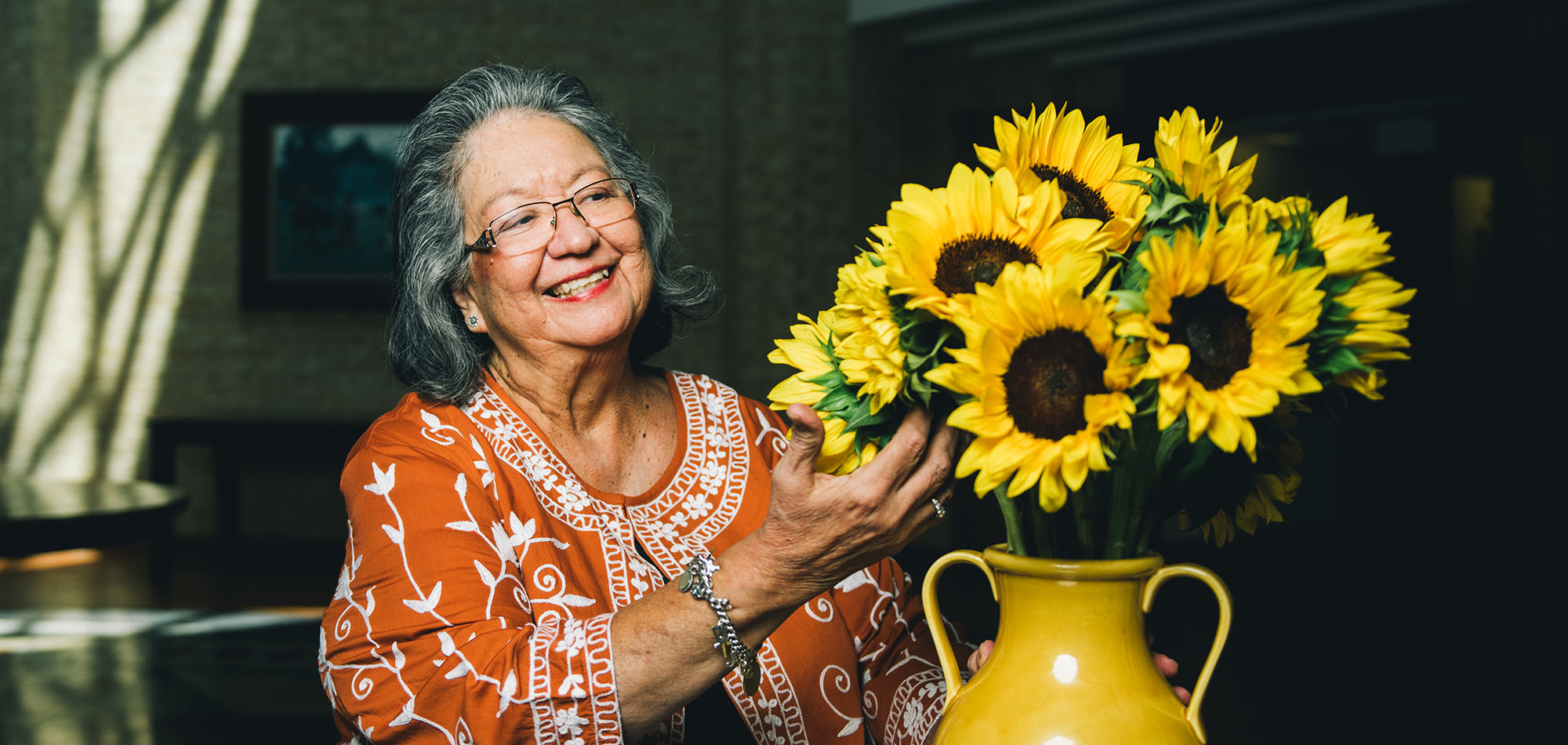 Susana Alemán looking at a vase of sunflowers