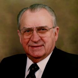 Portrait of Thomas M. Reavley, wearing glasses and a suit with a black jacket and black and gold tie.