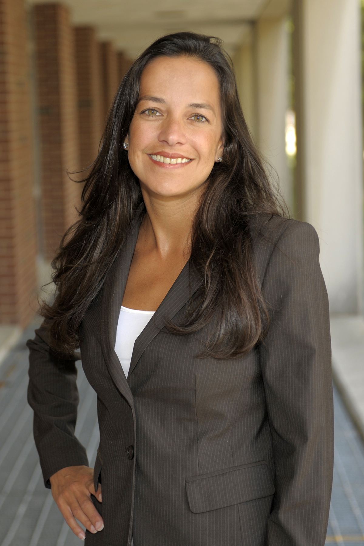 Portrait of Melissa Wasserman, wearing a white shirt and dark jacket with her right hand on her hip.