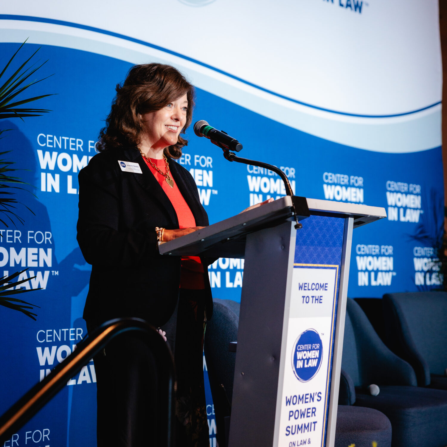 Photo of Jennifer Banda '98 standing at a podium on stage at CWIL's Power Summit