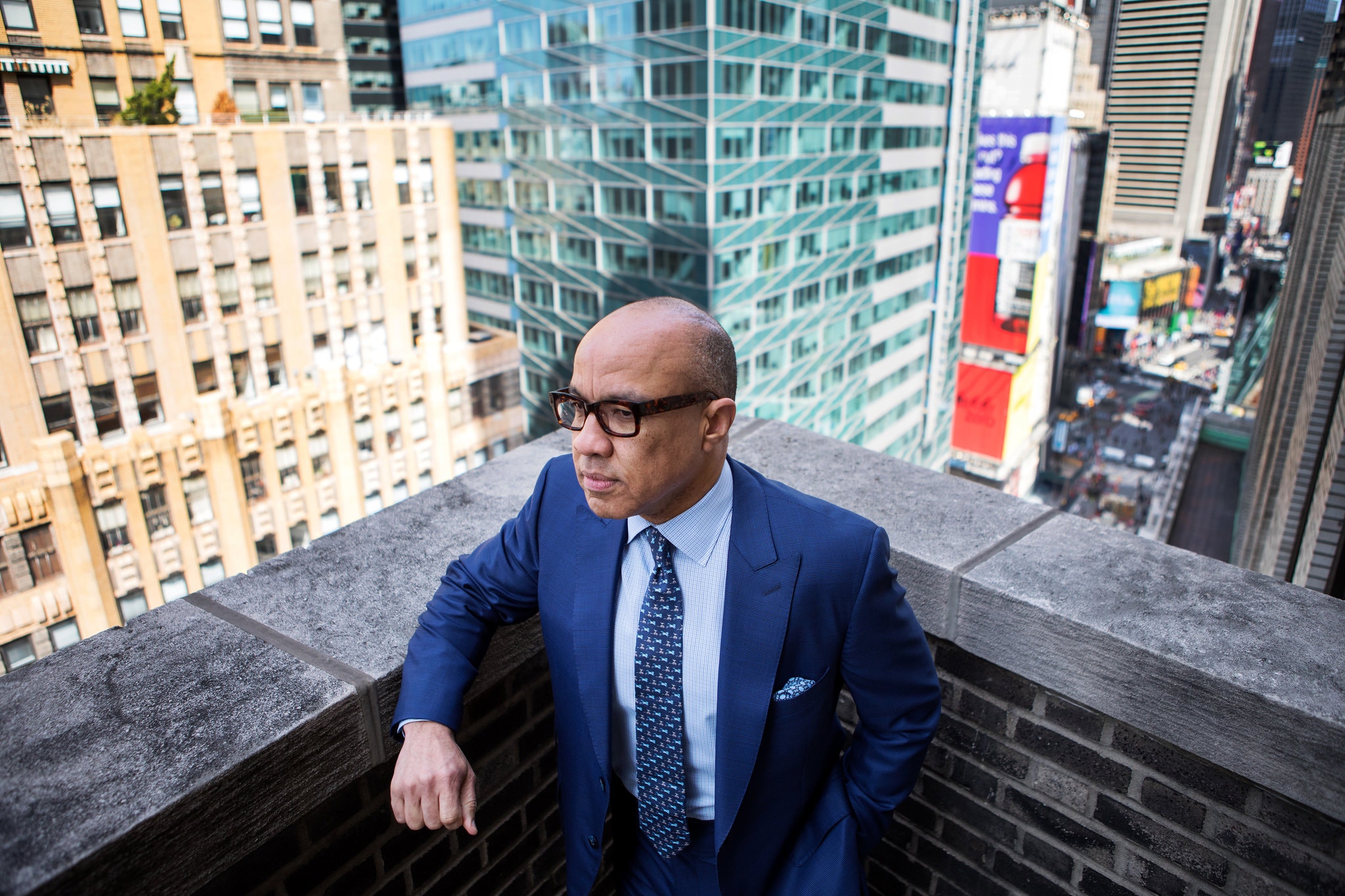 Darren Walker, wearing a blue suit, standing on a balcony in New York City