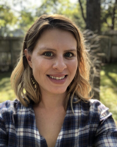 Portrait of Emily Bamesberger outside with trees behind her.