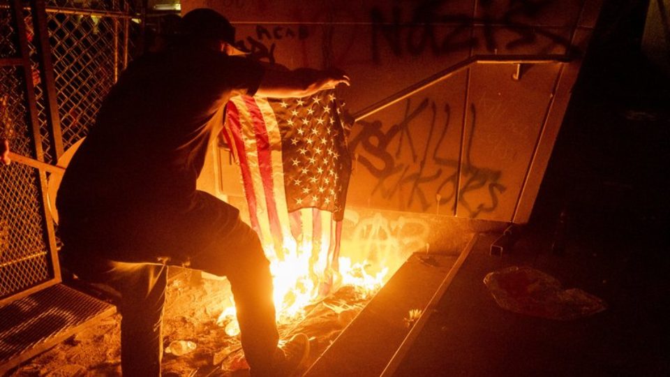 A person sets fire to a United States flag