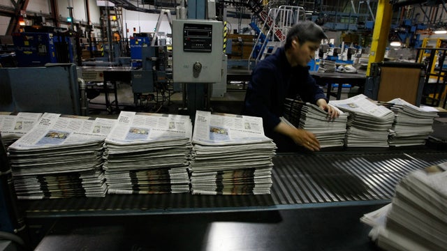 Newspapers lined up on a conveyer belt