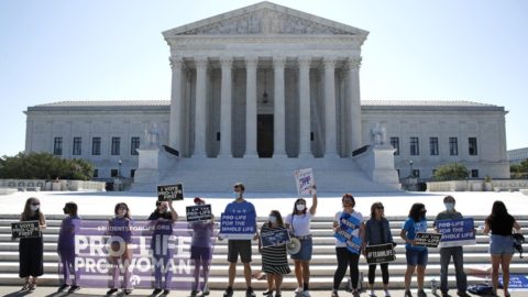 Protestors with pro-life signs stand in front of the U.S. Supreme Court