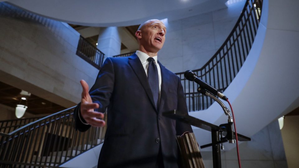 Carter Page speaking into a microphone in front of a staircase
